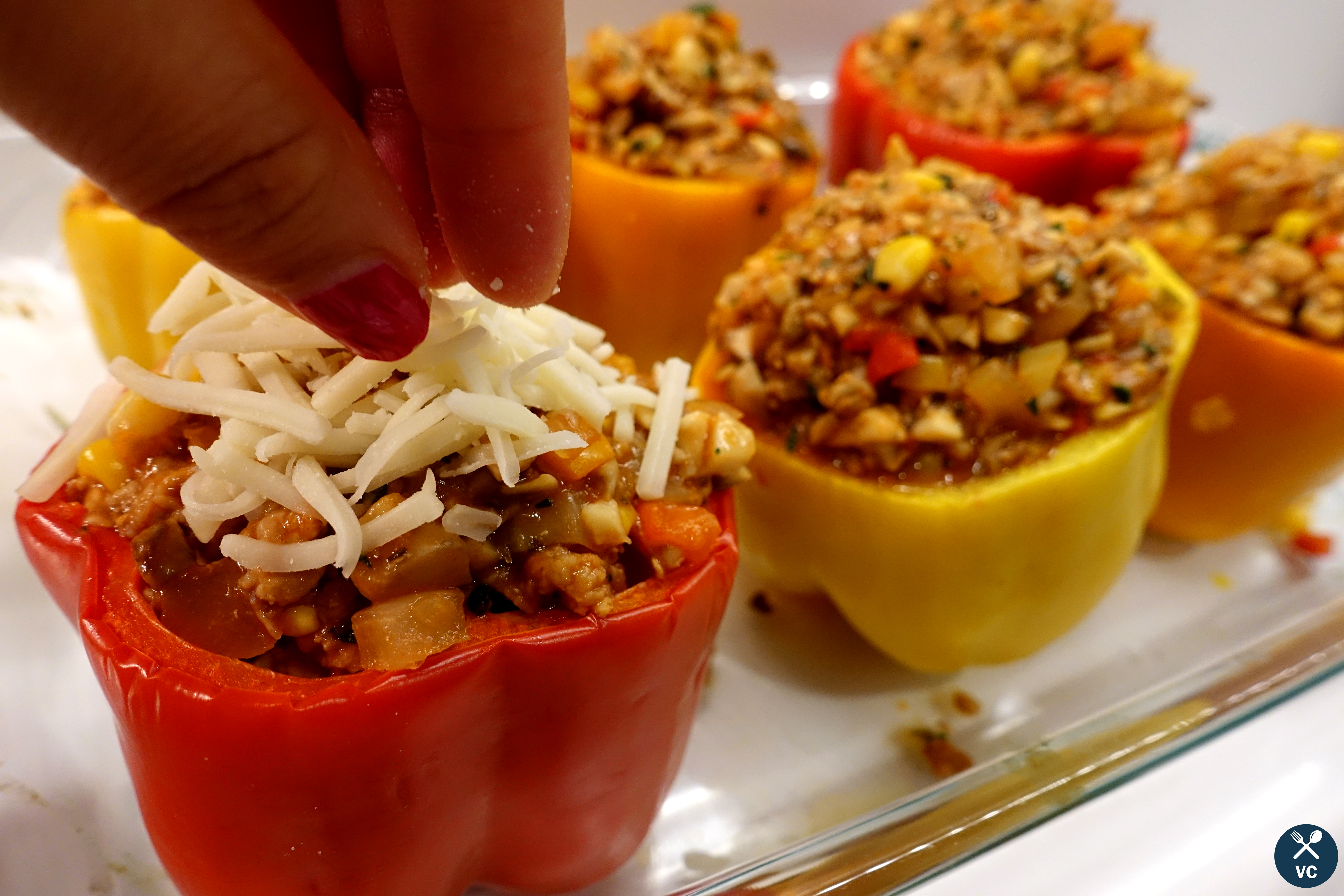 Sprinkling cheese on top of the turkey stuffed peppers (VC in the Kitchen)